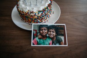 A Cake on a table with a picture of two smiling children.